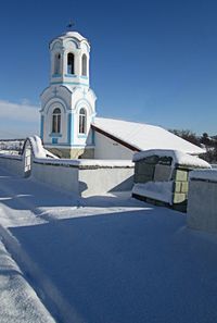 Church by building against sky during winter