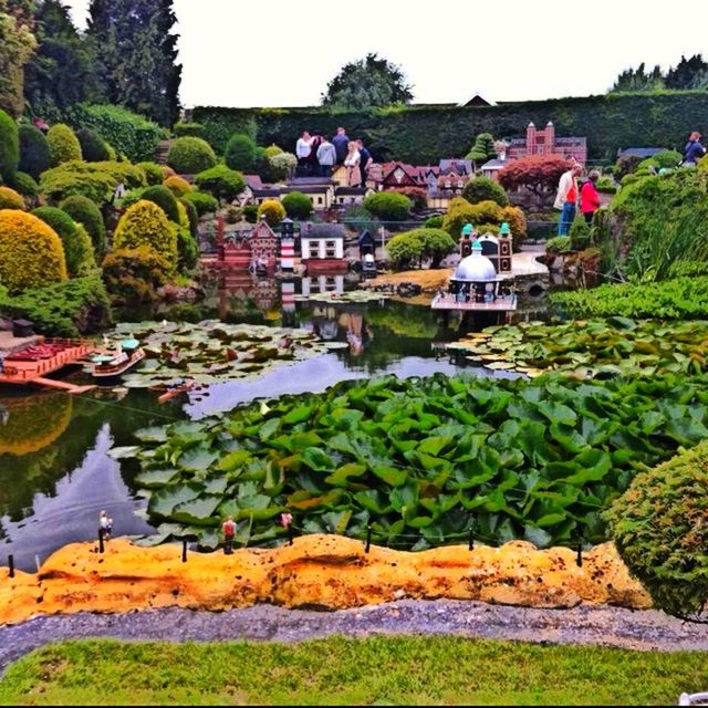 built structure, architecture, building exterior, water, green color, tree, plant, high angle view, growth, nature, river, day, pond, house, outdoors, beauty in nature, tranquility, sky, incidental people, clear sky