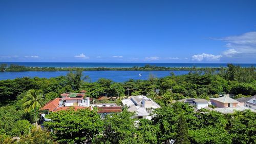 High angle view of houses by sea against blue sky