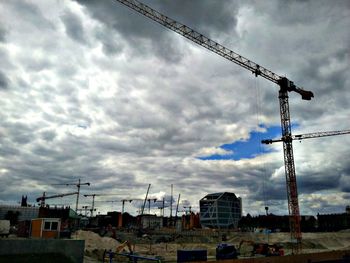Silhouette crane against cloudy sky