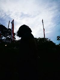 Silhouette man standing at beach against sky in city