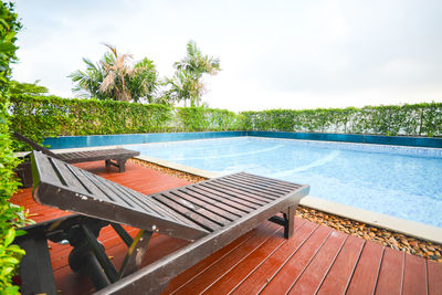 Chairs by swimming pool against sky