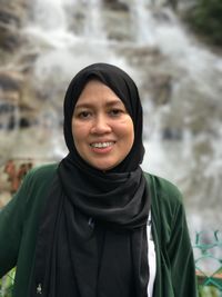 Portrait of smiling mature woman standing against waterfall