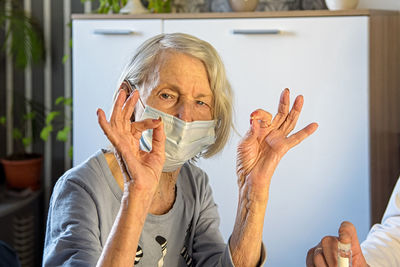 Caring doctor and a positive elderly grandmother in masks at home or in the hospital show ok. 