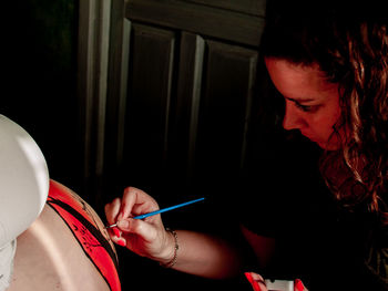 Woman painting on pregnant friend belly