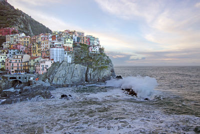 Buildings by sea against sky