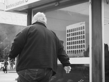 Rear view of man standing against wall in city