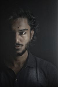 Close-up portrait of young man against black background