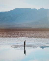 Full length of woman standing on cliff by sea