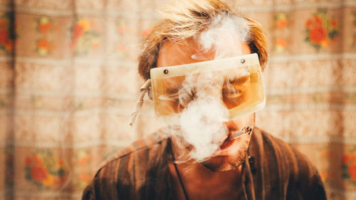 Man wearing protective eyeglasses while smoking cigarette