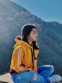 Young woman looking away while sitting on mountain