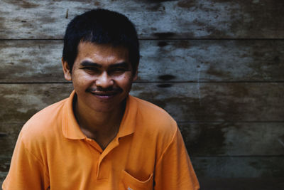 Portrait of smiling man against wooden wall