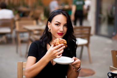 Portrait of young woman holding ice cream in cafe