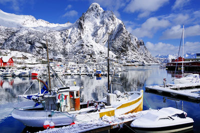Sailboats moored in lake by snowcapped mountains against sky