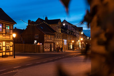 Illuminated street amidst buildings in city at night