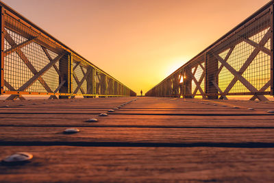 Surface level of suspension bridge against sky during sunset