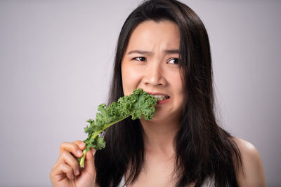 Portrait of woman holding ice cream against white background