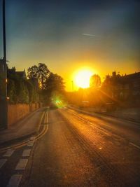 Road by city against sky during sunset