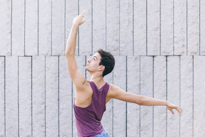 Rear view of young man dancing against wall