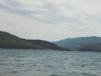 Scenic view of sea and mountains against sky