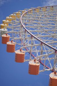 Low angle view of ferris wheel against blue sky