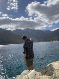 Rear view of man standing by mountain against sky