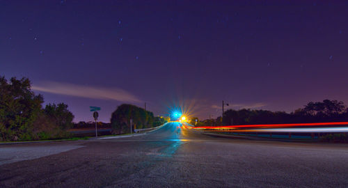 Light trails on road against sky at night