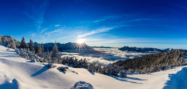 Panoramic view of snow covered landscape against blue sky