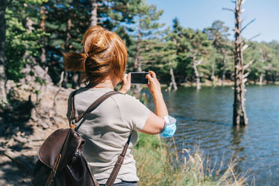 Rear view of woman photographing with umbrella