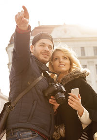 Portrait of happy young woman holding mobile phone in city