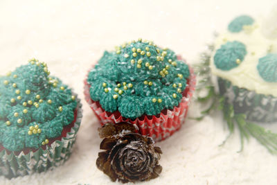 High angle view of christmas cupcakes with pine cone on snow