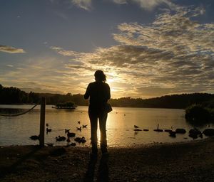 Silhouette man standing on beach against sky during sunset