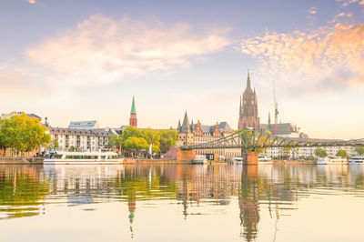 View of buildings and river against cloudy sky