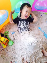 High angle view of girl crying covered in sand at beach