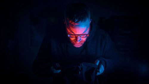 Close-up of man with lights on face against black background