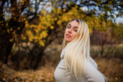 Portrait of young woman standing against trees