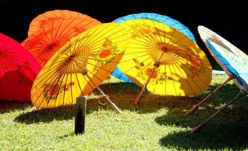 Multi colored umbrellas on field against sky