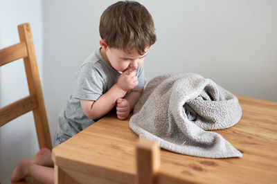 Cute toddler is clowning around at the kitchen table