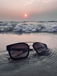 Close-up of sunglasses against sky during sunset