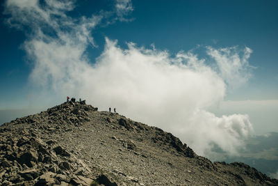 Low angle view of people on rock against sky