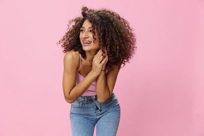 Portrait of young woman against pink background