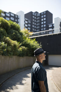 Man wearing hat standing against buildings in city