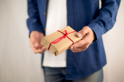 Midsection of man holding mobile phone in box