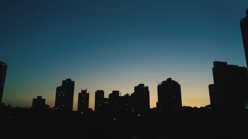 Silhouette buildings against sky at dusk