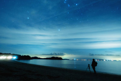 Silhouette people on beach against sky at night