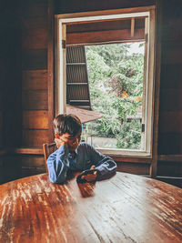 Full length of boy sitting on wooden floor at home