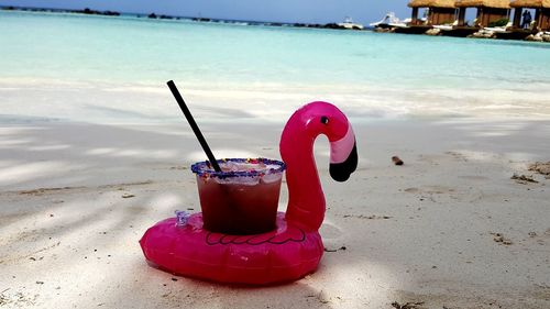 Red wine glass on sand at beach against sky