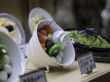 Close-up of fruits with cream in bowl on table at market stall