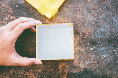 Close-up of person hand holding empty box against wall