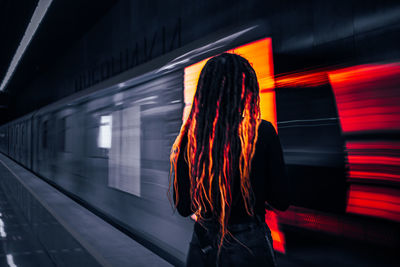 Rear view of woman standing at railroad station platform